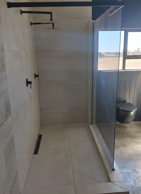 Frameless glass shower with rainhead